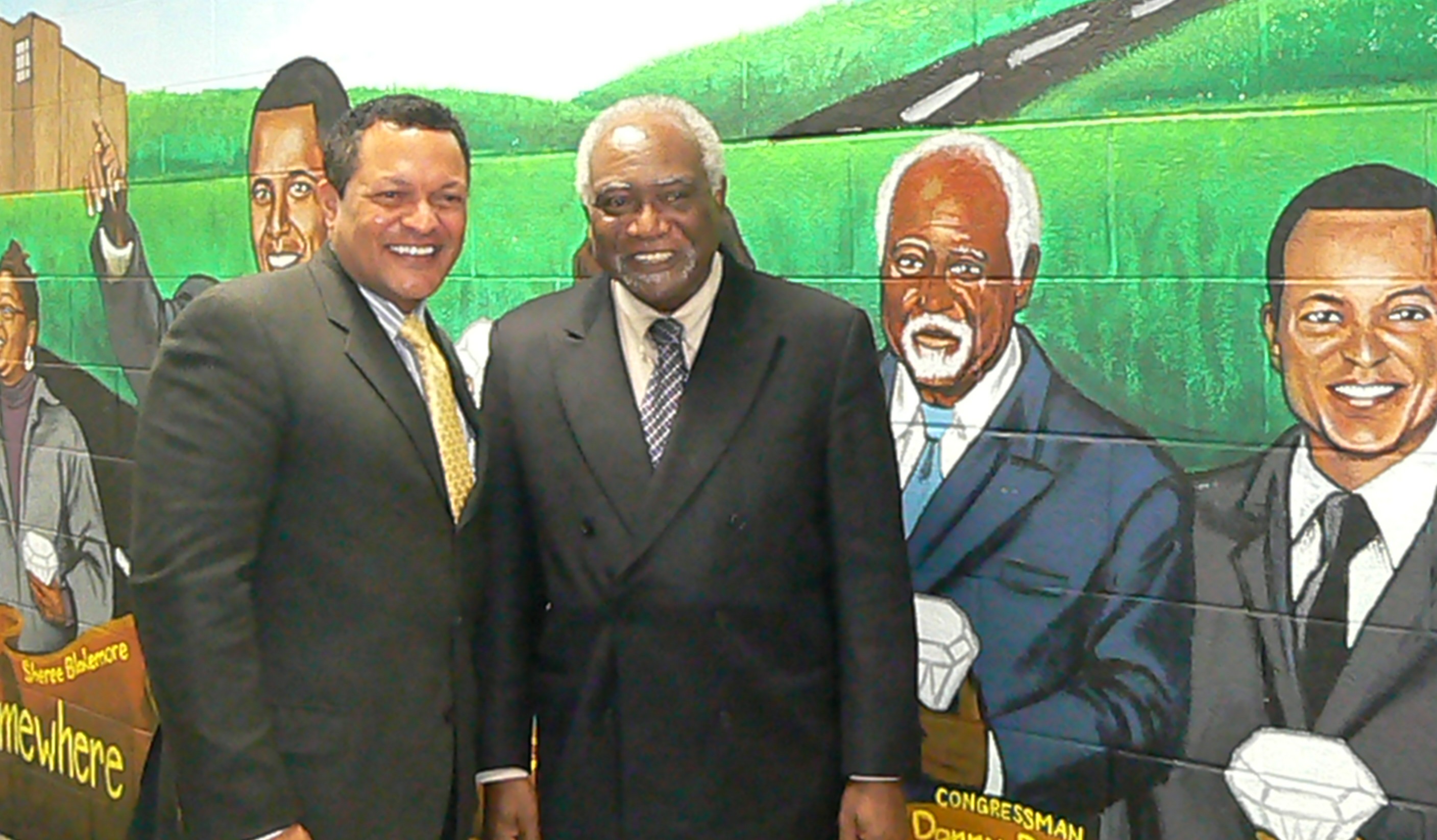 Cong. Danny Davis and Kenneth Morris stand beside their images painted in a mural at Frederick Douglass High School.